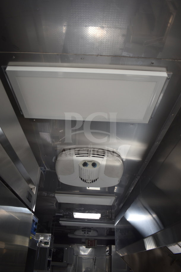 Interior of a 2021 Texino cooking trailer, featuring CaptiveAire hood, stainless steel surfaces, and ceiling ventilation.