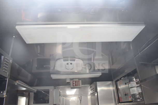 Inside view of a 2021 Texino 28ft cooking trailer, showing ventilation, stainless steel surfaces, and refrigeration units.