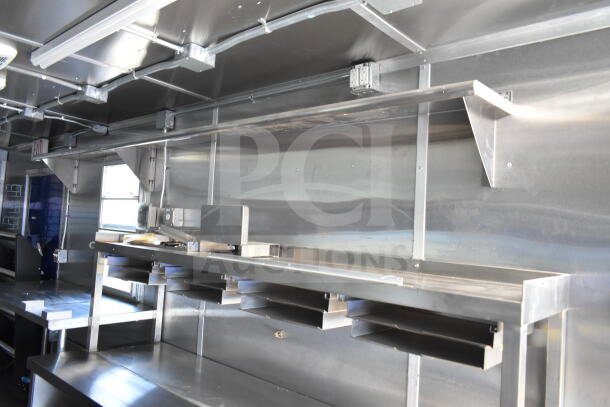 Rock Solid Cargo 8.5'x28' food trailer shell interior with CaptiveAire grease hood, stainless steel walls, and shelving. Ideal for outfitting.