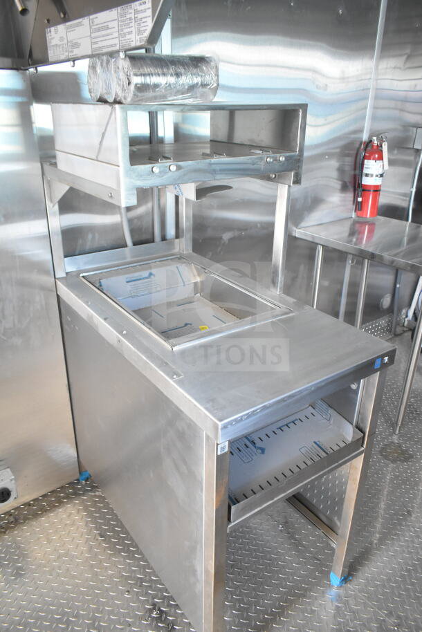 Inside view of a Rock Solid Cargo 8.5'x28' food trailer shell. Features a CaptiveAire grease hood, stainless steel surfaces, and fire extinguisher. Ready for equipment installation. VIN: 7H2BE2837ND041749.