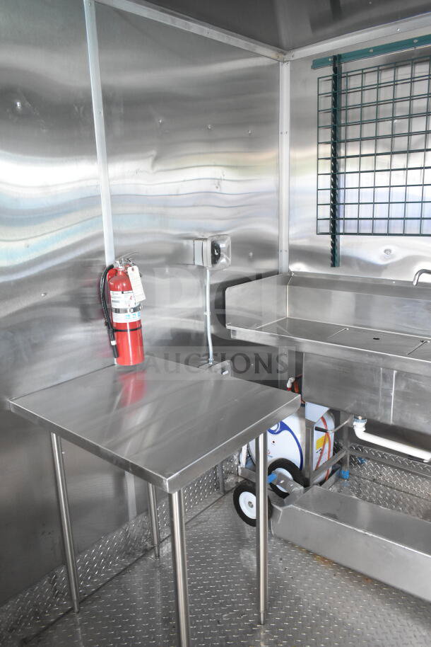 Rock Solid Cargo 8.5'x28' food trailer shell interior with CaptiveAire grease hood, stainless steel surfaces, and fire extinguisher.