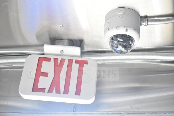 Ceiling view of Rock Solid Cargo 8.5'x28' food trailer shell, featuring an "EXIT" sign and a surveillance camera.
