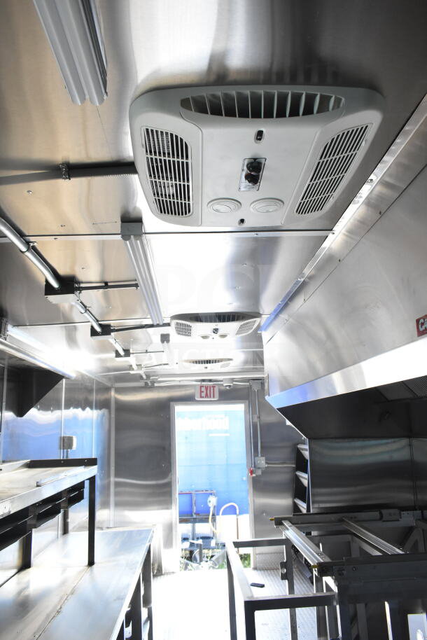 Inside view of Rock Solid Cargo 8.5'x28' food trailer shell featuring a CaptiveAire grease hood and stainless steel interior, ready for customization.