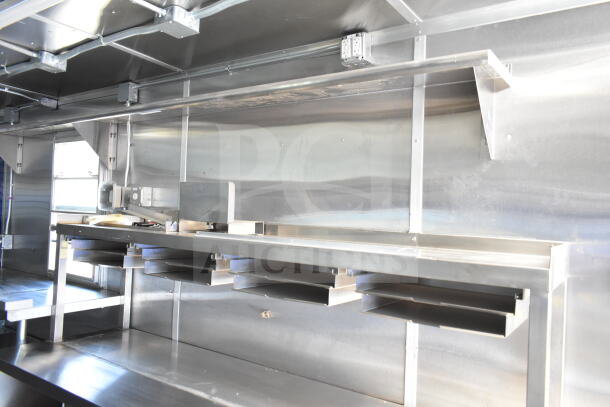 Rock Solid Cargo 8.5'x28' food trailer interior with CaptiveAire grease hood, stainless steel shelving, ready for equipment. VIN: 7H2BE2837ND041749.
