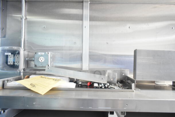 Interior of Rock Solid Cargo 8.5'x28' food trailer shell with CaptiveAire grease hood. Electrical outlets and unfinished metal surfaces visible.