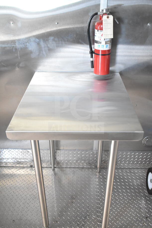 Rock Solid Cargo 8.5'x28' food trailer shell interior, metal worktable with fire extinguisher. Ready for customization.