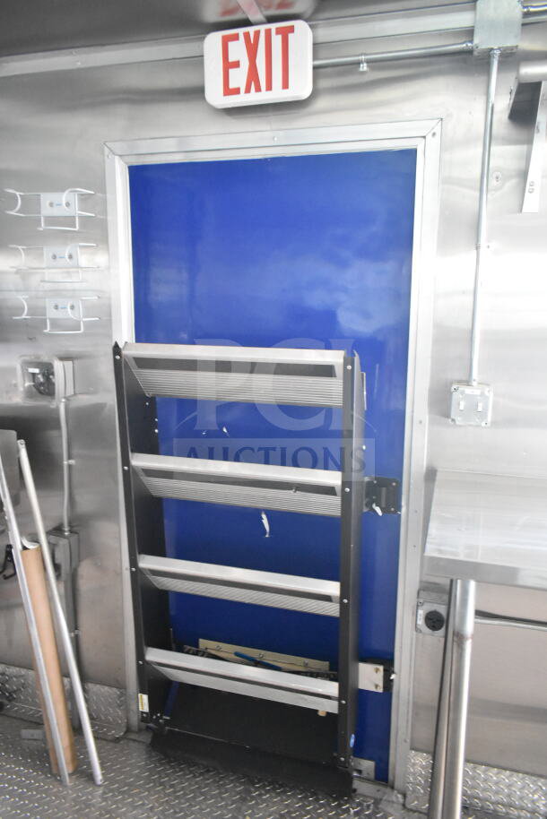 Rock Solid Cargo 8.5'x28' food trailer shell interior with blue door, EXIT sign, and CaptiveAire grease hood setup.