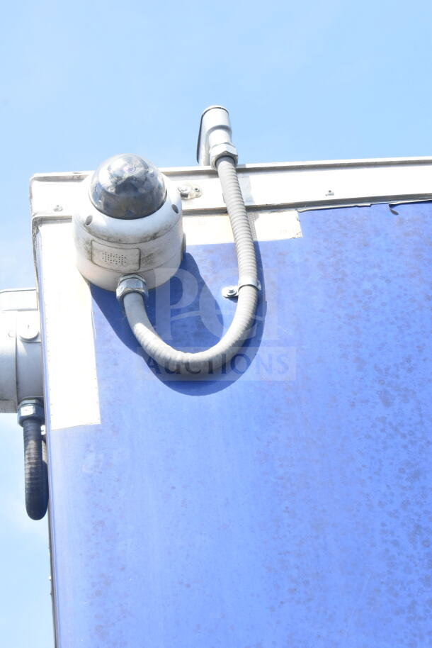 A dome security camera attached to a blue food trailer roof, visible wiring along the side.