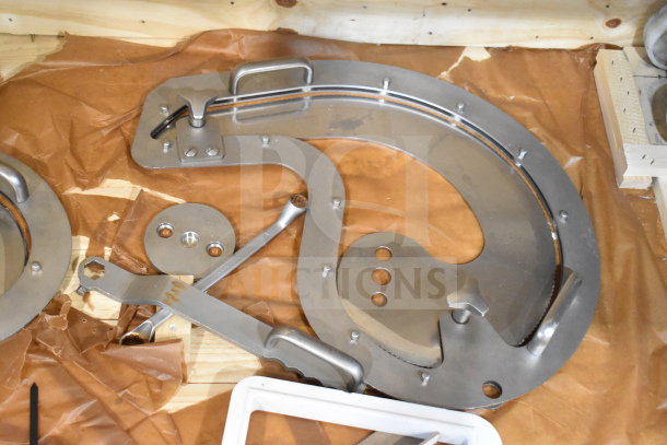 Treif Puma slicer parts, stainless steel components, clean condition, with handles and brackets, on brown wrapping.