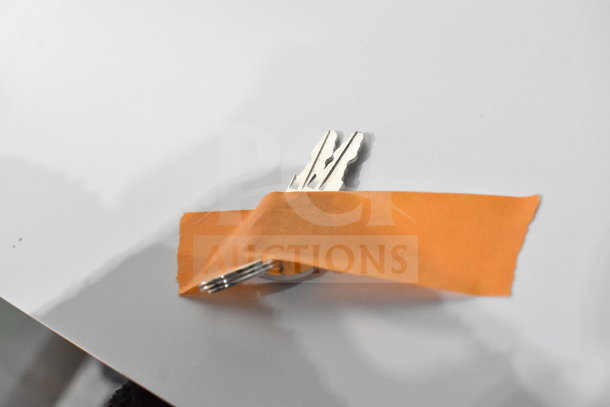 A set of keys partially covered by orange tape on a white surface.