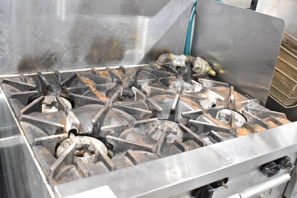 Garland SunFire X36-6R commercial 6 burner gas range with oven, over shelf, and backsplash. Used condition with visible wear.