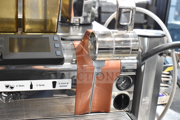 Thermoplan Mastrena M2-CS espresso machine with LCD display, hoppers, steam wand, gauges displayed. Stainless steel finish.