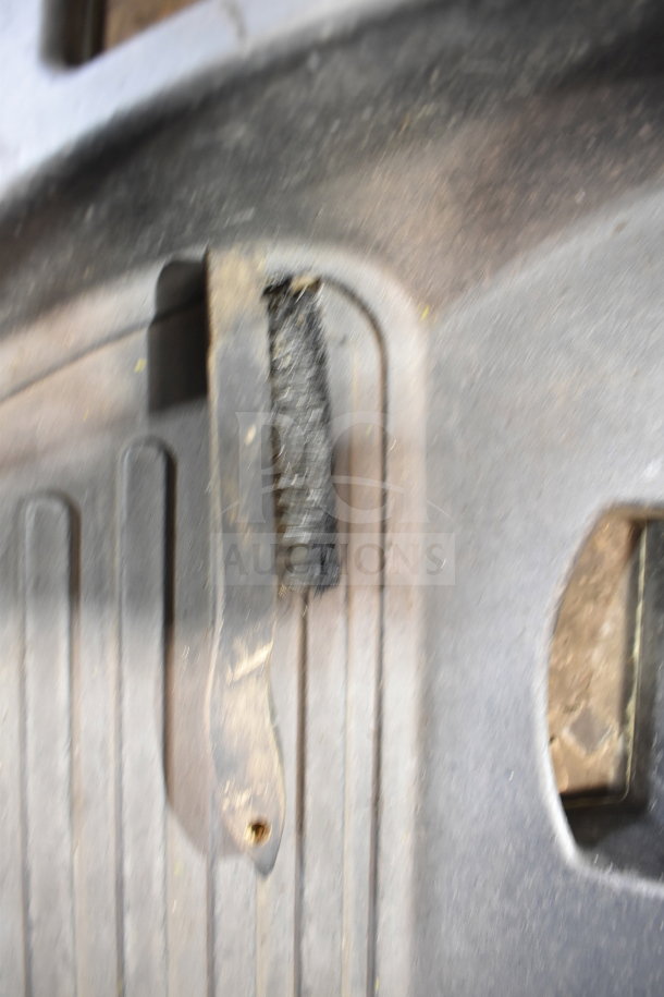 Blurred image of a worn component of a JohnBeam 1200P floor style balancer, showing texture and surface details.