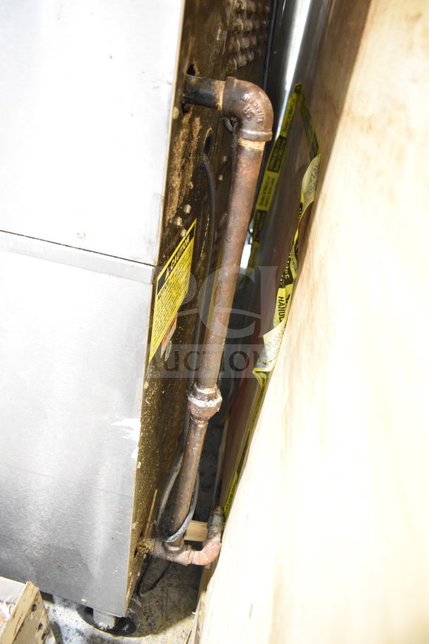Rear view of Vulcan SG4D-4 convection oven on casters, showing rusted pipe and caution label.