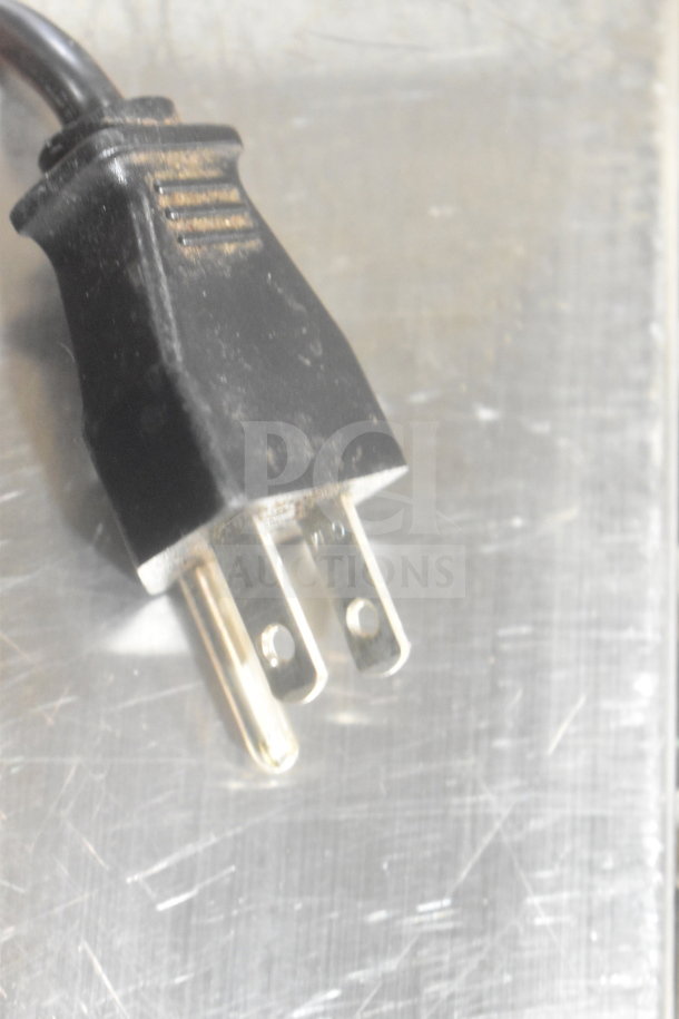 Close-up of a black electrical plug on a metal surface. Part of auction lot with POS monitor, Bixolon SRP-S300, and Epson printer.