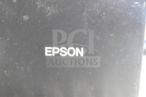 Epson label on a device surface, indicating brand of included receipt printer in auction lot.