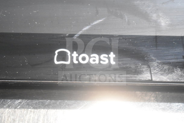 POS monitor featuring Toast branding, black casing, surface scratches visible.