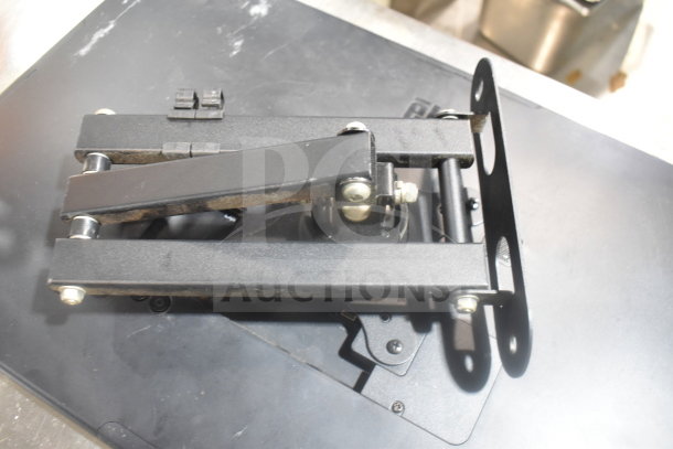 POS monitor mount with hinged arms on a black surface. Slight wear visible.