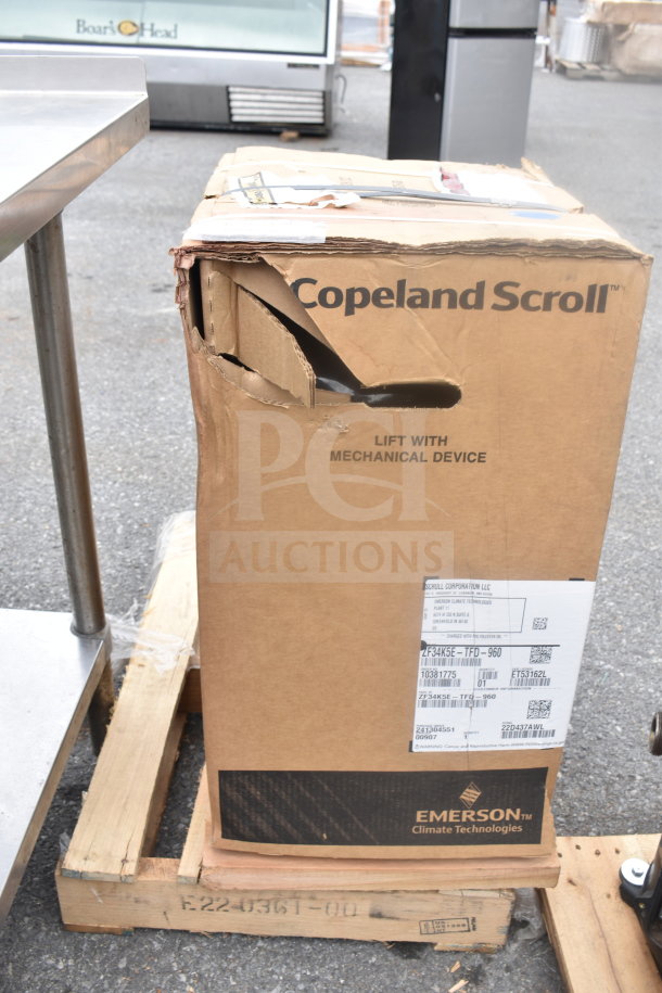 Emerson ZF34K5E-TFD-960 compressor in a damaged Copeland Scroll box, on a pallet. Tags indicate model and details.