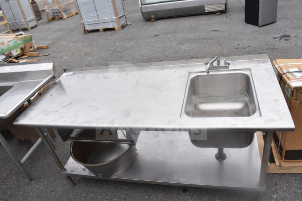 Commercial stainless steel table with sink bay and under shelf. Features faucet, sturdy legs, and lower storage space. Good condition.