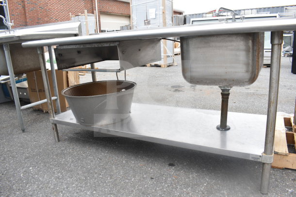 Stainless steel commercial table with sink bay, under shelf, and visible wear. Ideal for restaurant use.