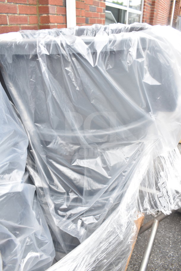 Six gray poly trash cans wrapped in clear plastic, stacked for auction. Durable, multipurpose use. New condition.