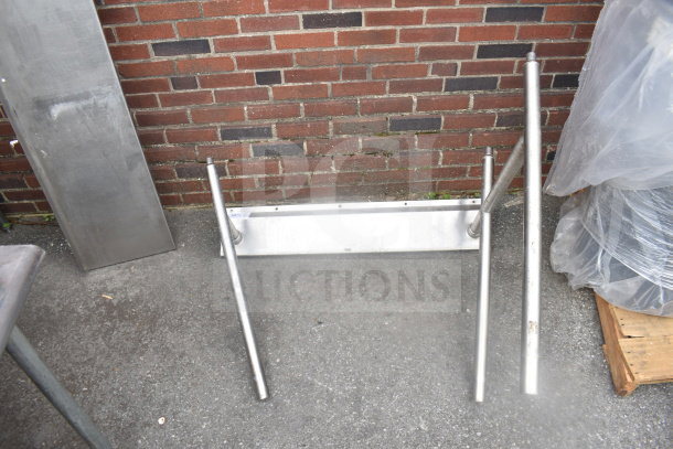 Stainless steel metal legs with mounting base, in good used condition, against a brick wall backdrop.