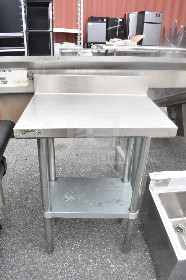 Regency commercial table with backsplash and under shelf, stainless steel, visible wear on lower shelf, sturdy legs.