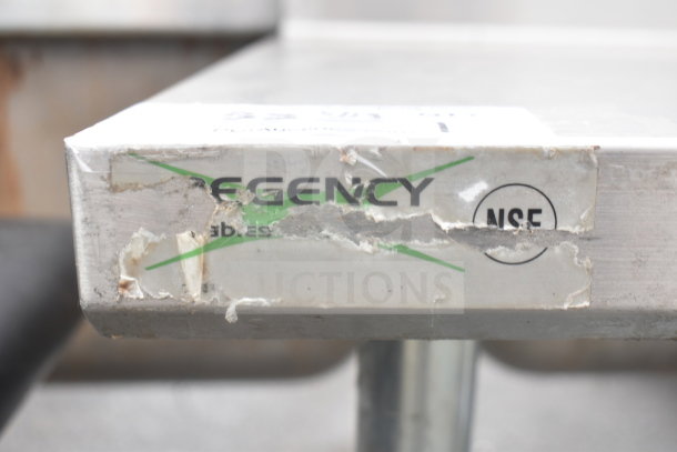 Regency commercial table corner with damaged label showing NSF mark. Features backsplash and undershelf. Ideal for kitchens.