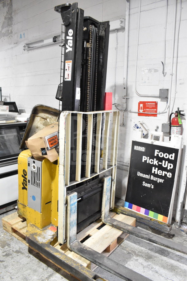 Yale E Industrial Walkie Stacker, yellow and black, walk-behind design, visible wear, includes safety labels.