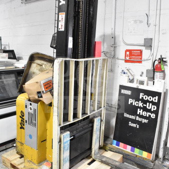 Yale E Industrial Walkie Stacker, yellow and black, walk-behind design, visible wear, includes safety labels.