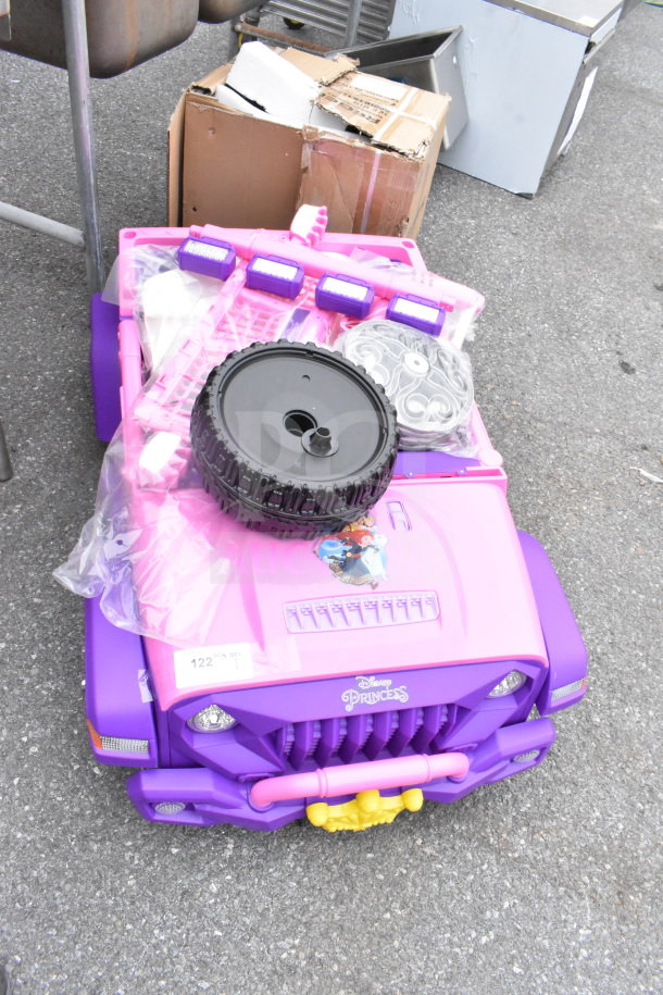 Pink and purple Disney Princess ride-on vehicle for children, new condition, includes tire and accessories, visible princess graphics.