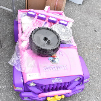 Pink and purple Disney Princess ride-on vehicle for children, new condition, includes tire and accessories, visible princess graphics.