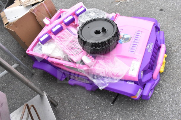 Pink and purple princess ride-on vehicle, partially assembled, featuring Disney branding. Condition appears new in packaging.
