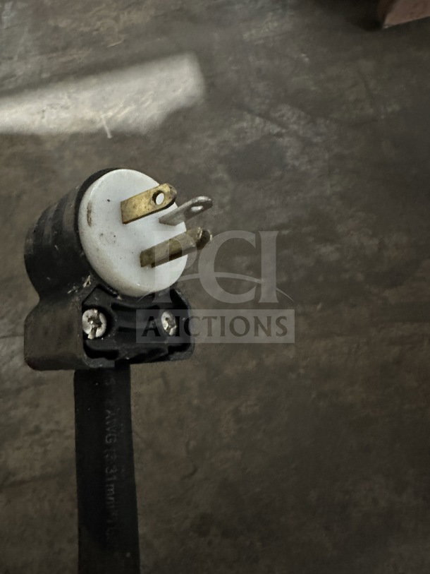 Close-up of a heavy-duty electrical plug on a power cord, featuring three metal prongs and a round white base.