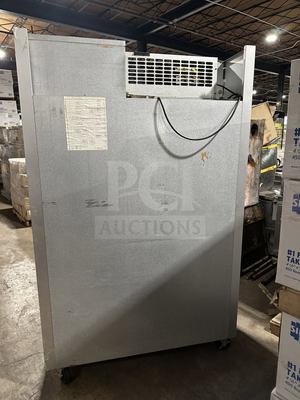 Traulsen G21000 commercial refrigerator back view, stainless steel, on casters, with visible wiring and label, in used condition.