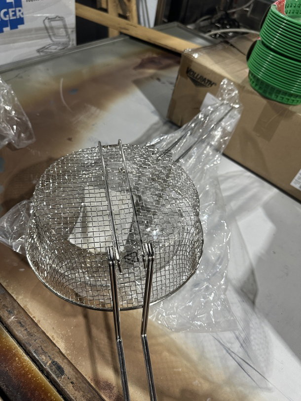 Brand new Winco 10" heavy-duty medium-mesh round fry basket, Model FB10M. Features sturdy metal construction.