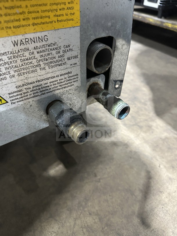 Imperial commercial stainless steel natural gas fryer with back splash and casters; shown close-up of gas connections and warning label.