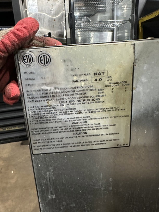 Imperial stainless steel natural gas deep fat fryer with backsplash, on casters. Safety and operation labels visible.