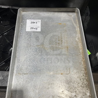 Commercial aluminum full-size baking sheet pan, used condition. Tags show quantities for auction bidding: 28X and 29X.