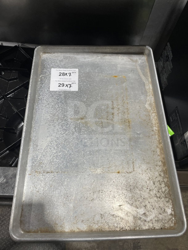 Commercial full-size aluminum baking sheet pan, pre-owned, showing signs of use. Auction label indicates 7X bid value.