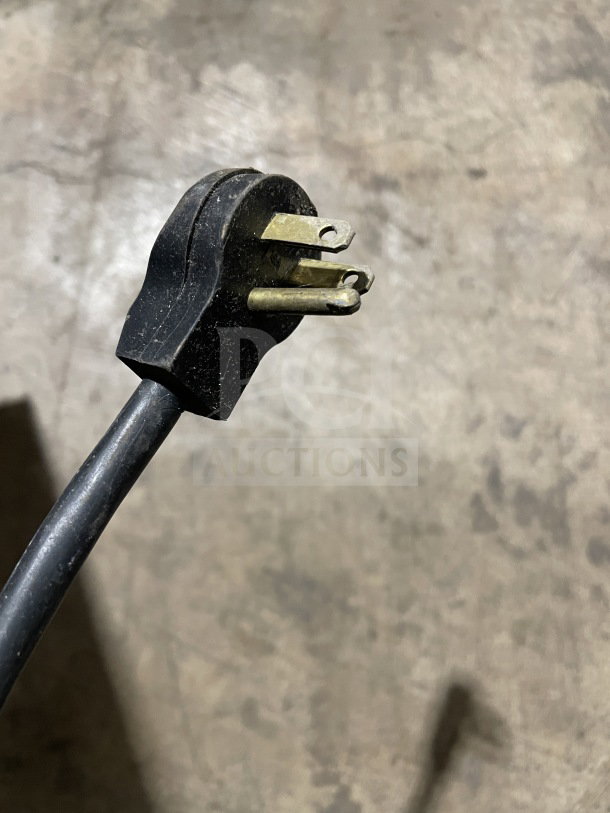 A black electrical plug for Kool-It LX-46FB freezer, showing prongs and wire against a textured surface.
