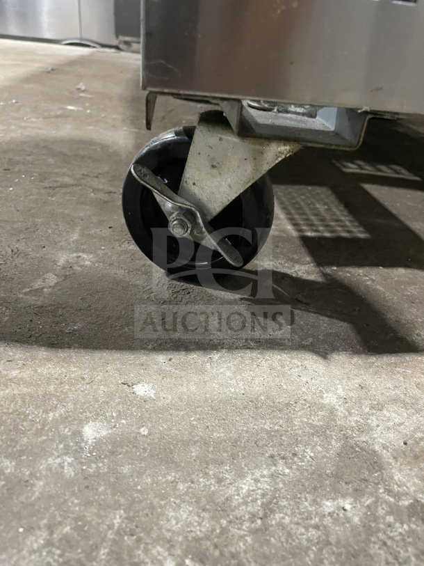 Caster wheel detail of Turbo Air TST-72SD-30-N 3-door refrigerated prep table, stainless steel construction, on casters.