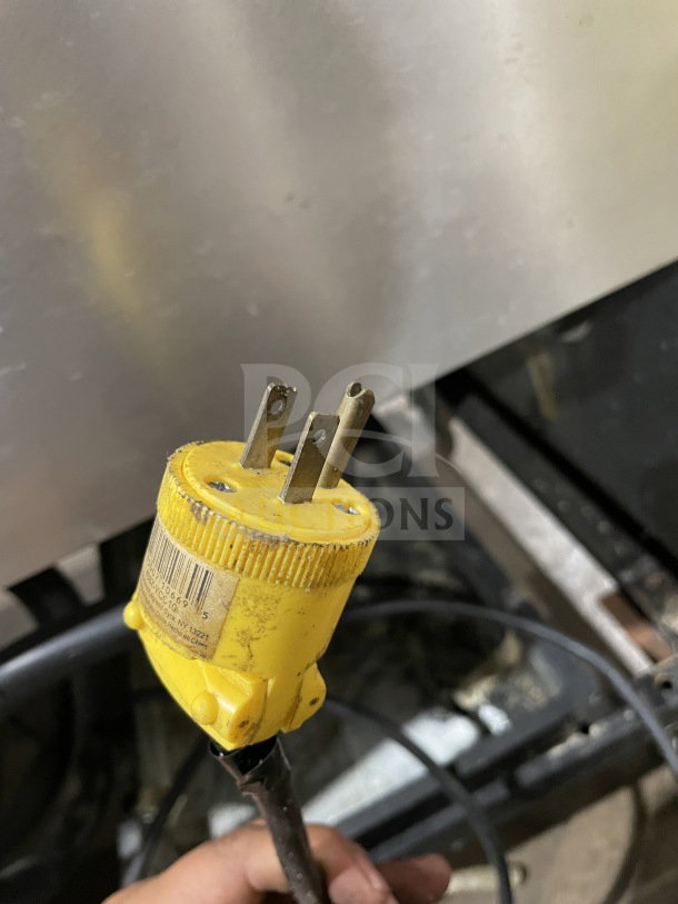 Yellow electrical plug and wire of True T-49 model commercial refrigerator. Yellow casing shows product barcode and details.