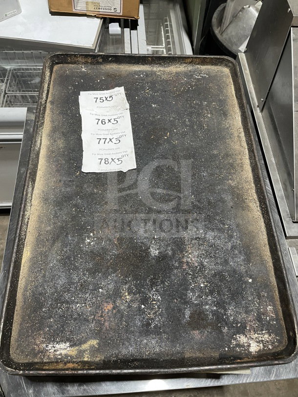 Commercial aluminum full-size baking sheet pan, well-used, with visible wear and patina. Auction tag showing bids attached.