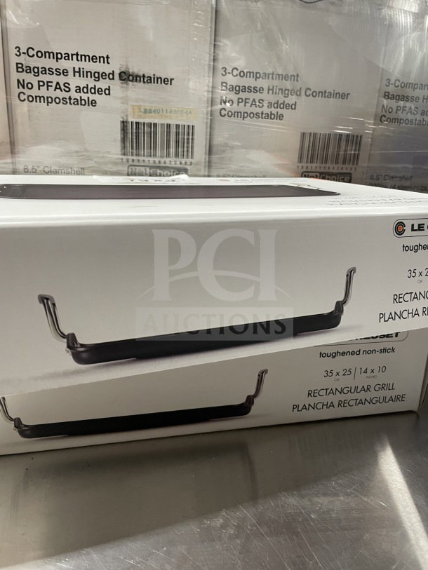 Brand new Le Creuset Toughened Nonstick 10"x14" rectangular griddle. Box shows griddle image and specs.