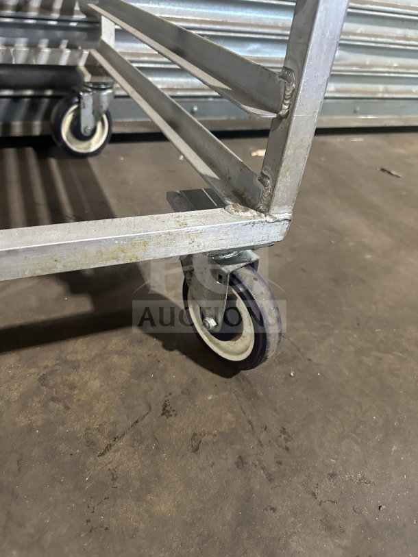 Commercial stainless steel heavy-duty sheet pan rack with visible casters, showing some signs of use.