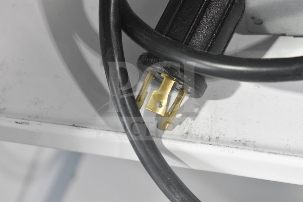 Close-up of electrical plug for True TRM3M commercial merchandiser, showing gold prongs and black cable, suitable for 208-240V.