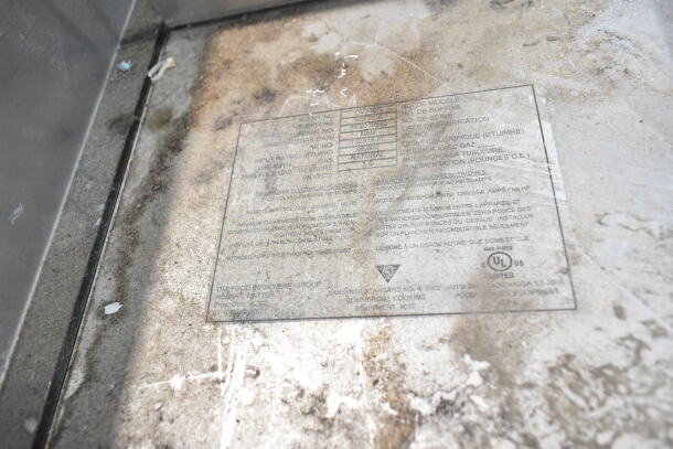 Baxter OV310G commercial rack oven plate detailing model number, BTU rating, and manufacturer info. Surrounded by wear marks.