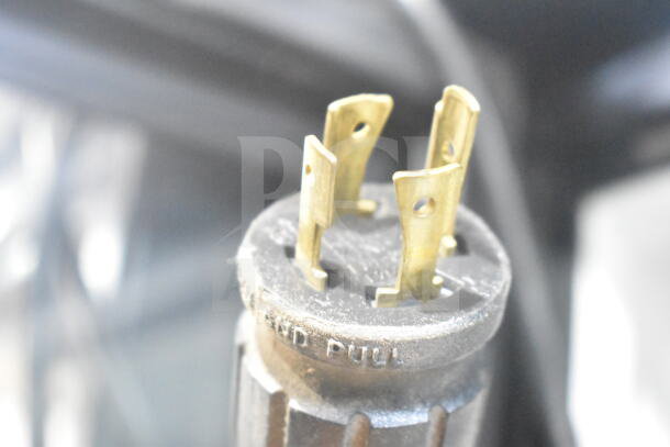Close-up of a metal plug showing its prongs and the text "AND PULL," indicating its connection use.